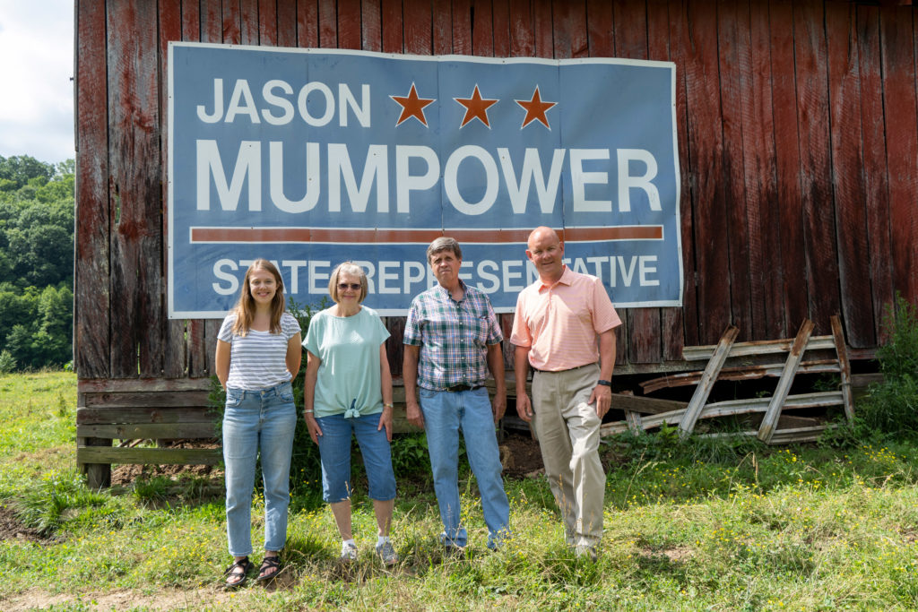 Jason Mumpower and the Stone family in front of their rustic barn with Mumpower's campaign sign