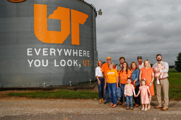 Several generations of Crafton family members standing next to the Everywhere You Look grain bin. All the people pictured are wearing orange and white or Tennessee Volunteers gear