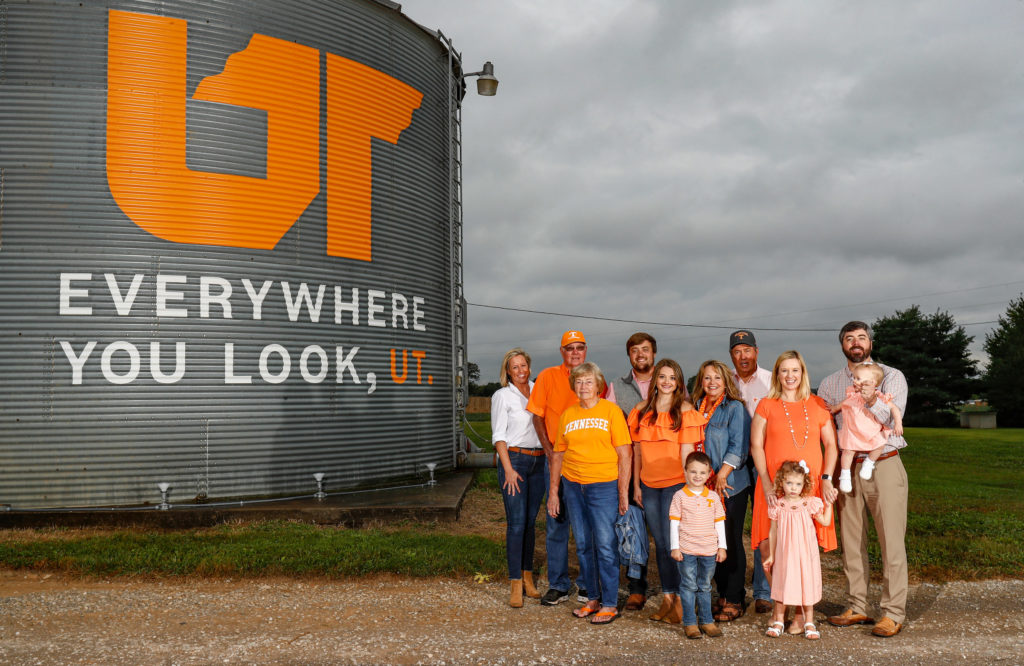 Several generations of Crafton family members standing next to the Everywhere You Look grain bin. All the people pictured are wearing orange and white or Tennessee Volunteers gear