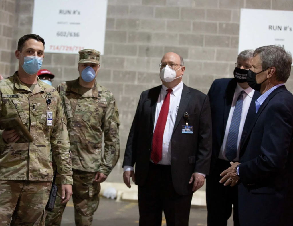 officials in masks inspect an alternate care hospital site