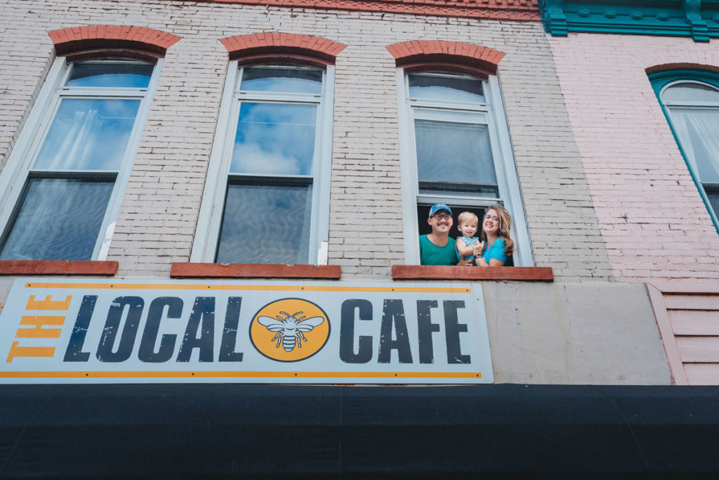 The Bartlett family look out the upstairs window above the Local Cafe sign