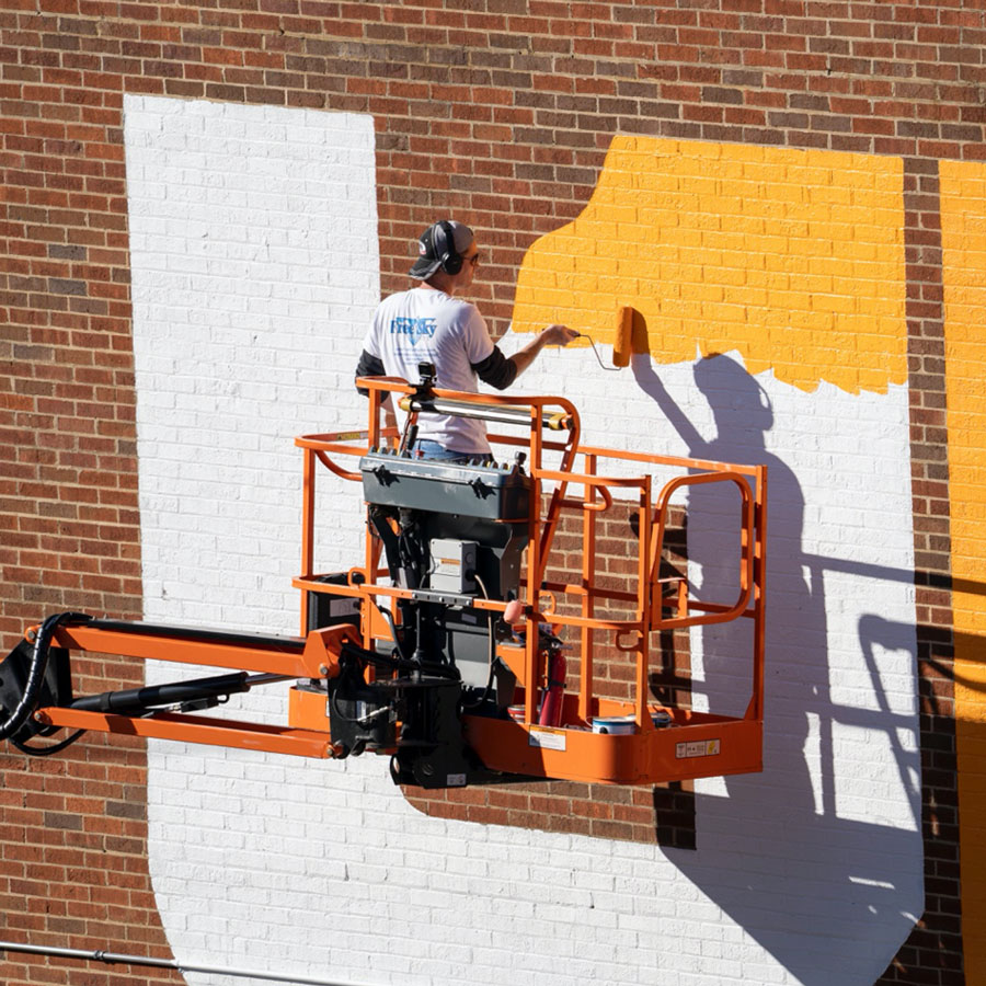 Troy Freeman painting the UT icon on a brick wall
