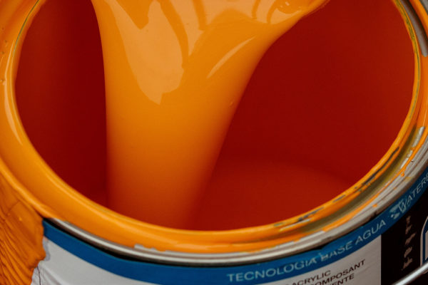 Orange paint pouring into a paint can