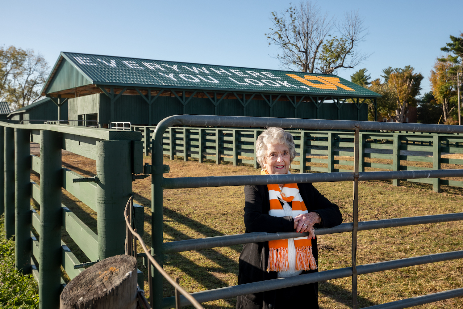Owner Rena Johnson standing in front of UT mural on green barn roof in White County
