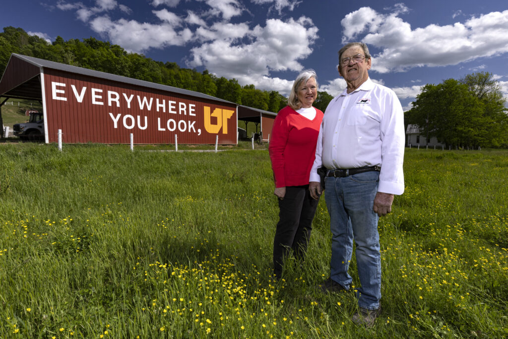 Bill and Debbie Young stand in front of their barn featuring an Everywhere You Look, UT mural in Pulaski, Tennessee