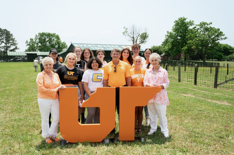 UT President Randy Boyd, Rena Johnson and Cynthea Johnson Amason pose in front of the UT mural at Johnson Farm with a group of White County High School graduates attending UT campuses in fall 2023 and whom are recipients of the Johnson Family UT System Scholarship