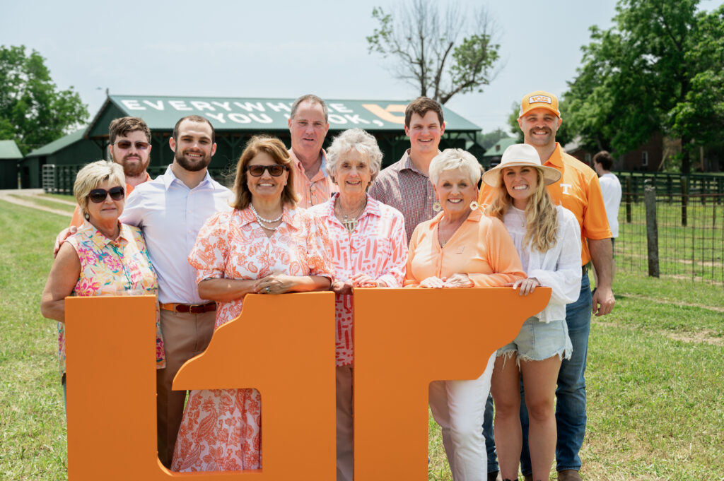 Family and friends posing in front of the UT mural during the dedication at Johnson Farm held May 26, 2023
