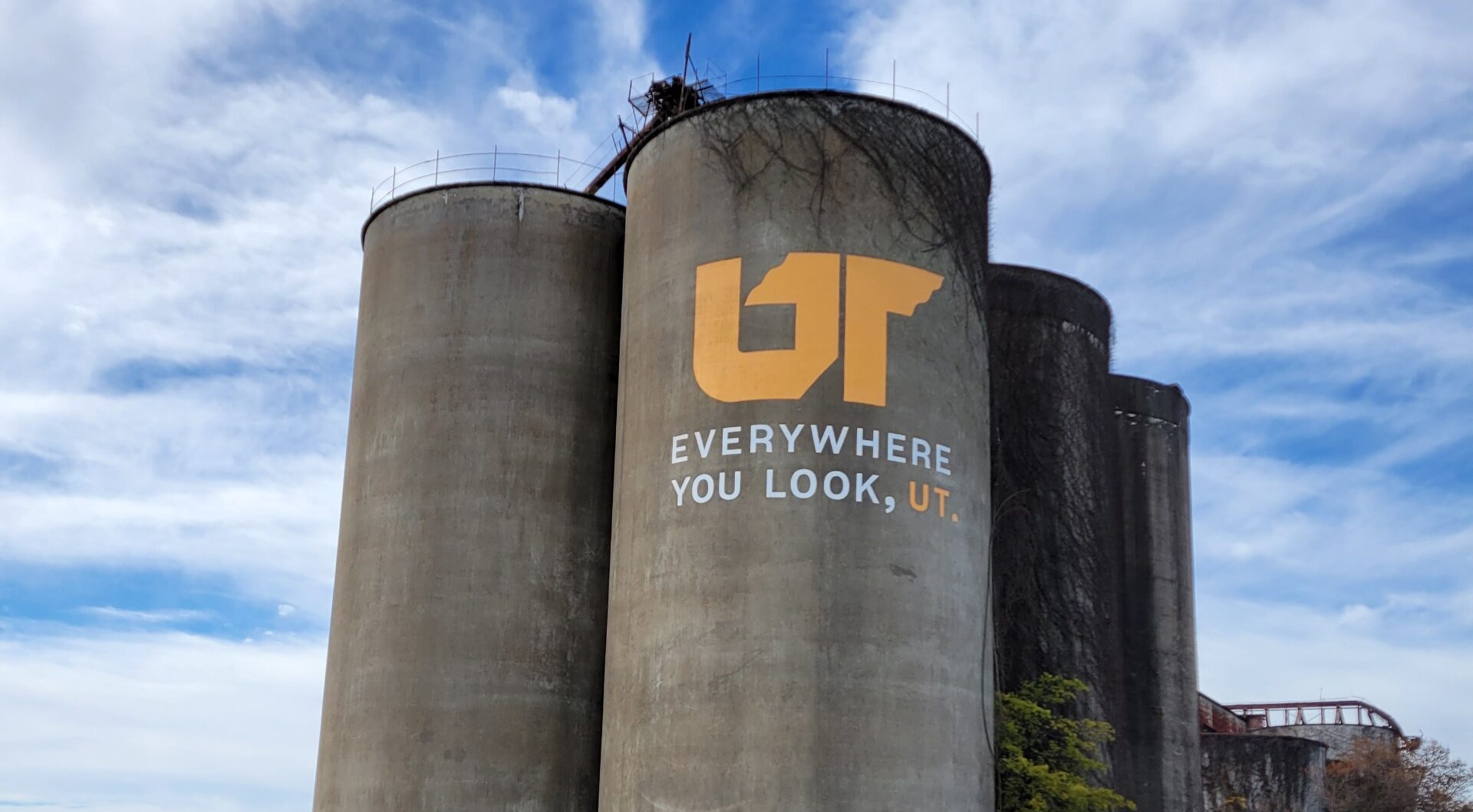 Orange and white "Everywhere You Look, UT" mural painted on concrete grain silo