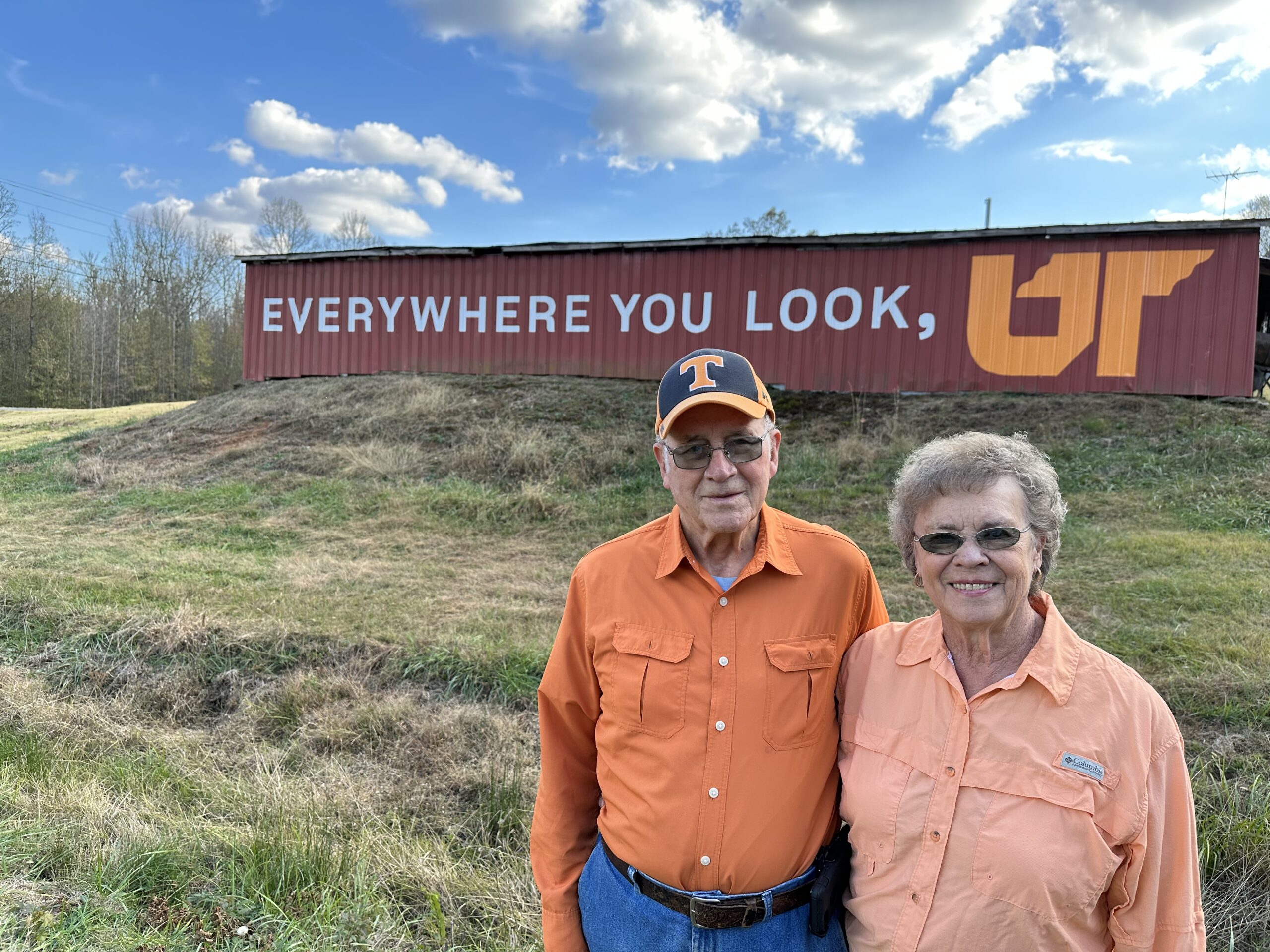 UT alumni Charles and Joyce McBride pose in front of Everywhere You Look, UT mural painted on their red barn