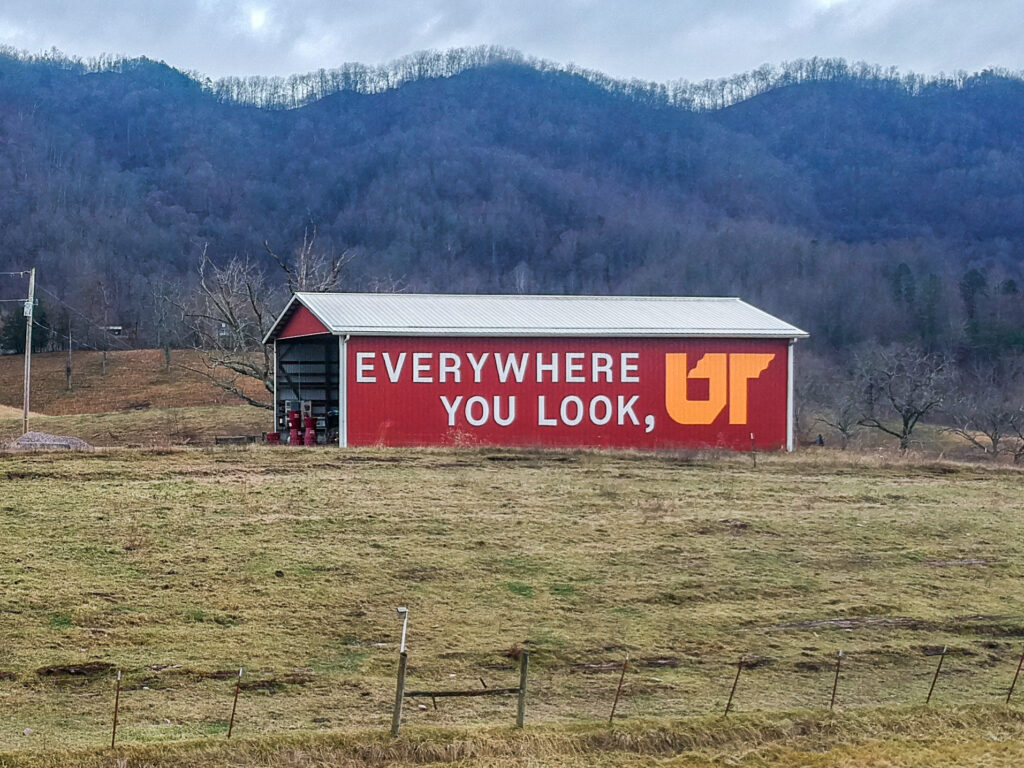 Orange and white Everywhere You Look, UT mural on red barn