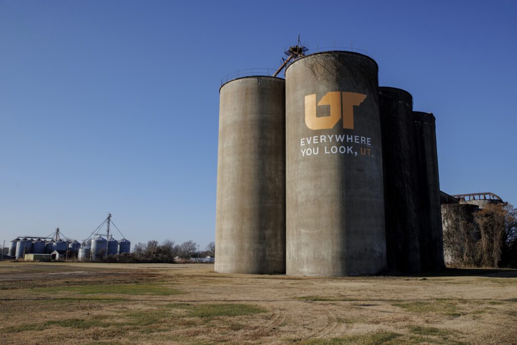 Aerial photo of concrete silos painted with orange and white Everywhere You Look, UT mural