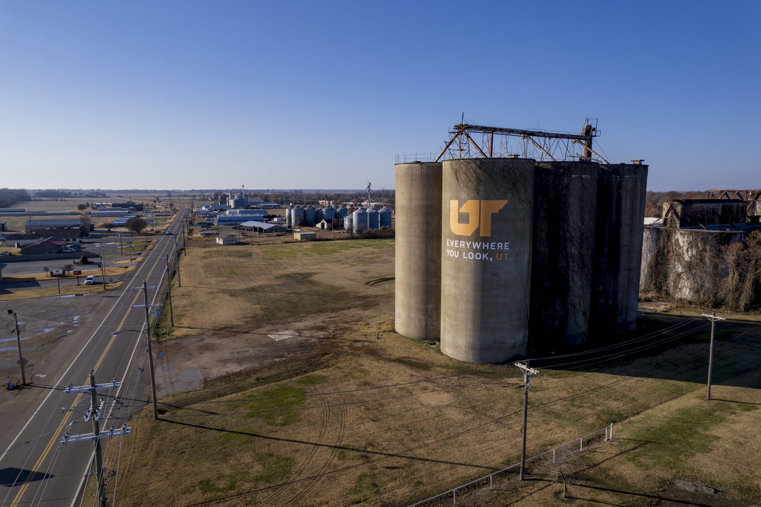 Aerial photo of concrete silos painted with orange and white Everywhere You Look, UT mural