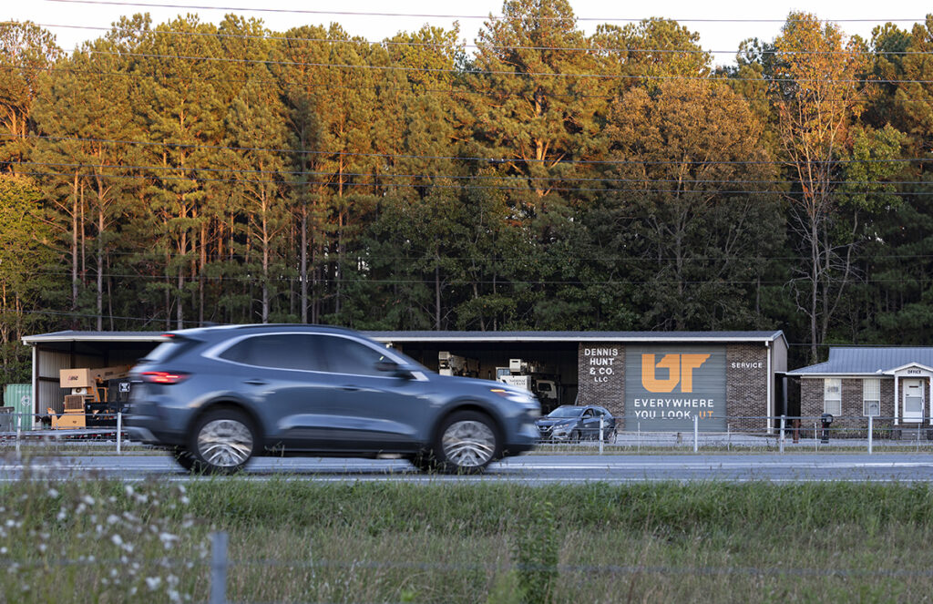 Small brick building with metal roofing and construction vehicles parked underneath.